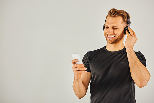 A man wearing headphones, immersed in music playing on his phone.