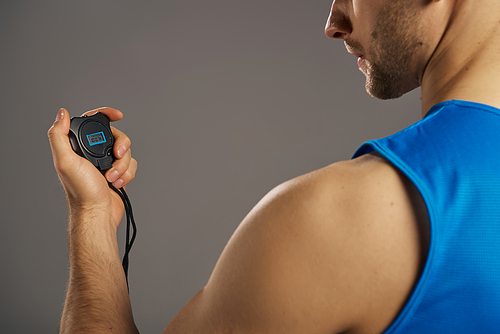 A man in a blue tank top is seen holding an electronic timer.