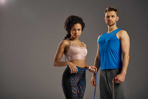 A multicultural couple in activewear poses for a fitness video, showcasing their strength and vitality in a studio setting.