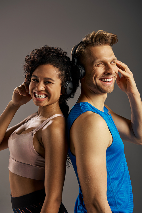 A young multicultural couple in active wear smiling while wearing headphones.