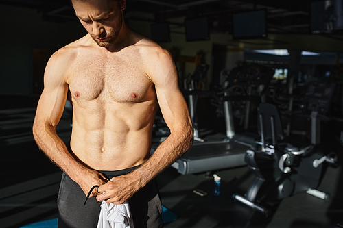 A muscular man displaying his strength while working out shirtless in a gym.