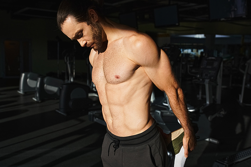 A muscular man without a shirt working out intensely in a gym, showcasing his strength and dedication.