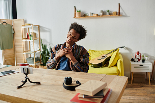 A young man is sitting at a desk, working on his phone and talking on the phone.