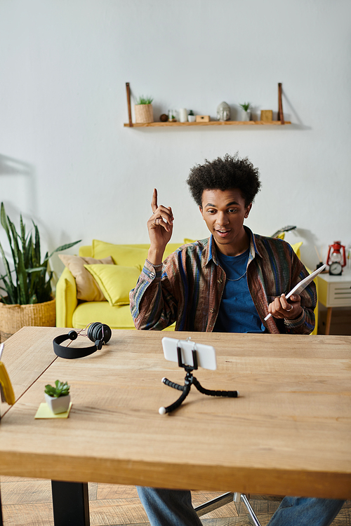 A young African American male blogger using a tablet and talking on the phone.