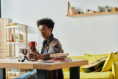 Young man holding phone camera, enjoying coffee.