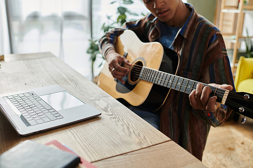 A man serenades with an acoustic guitar in front of a phone.