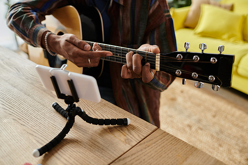 A man skillfully plays an acoustic guitar on a stand.