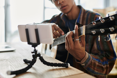 Man plays guitar in front of phone while recording a vlog.