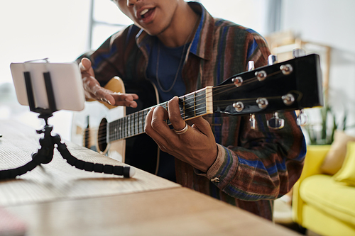 Young man passionately plays acoustic guitar at outdoor venue.