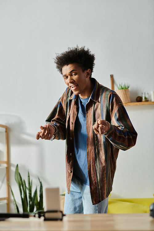 A young African American man, standing in front of a television, speaks to a phone camera.