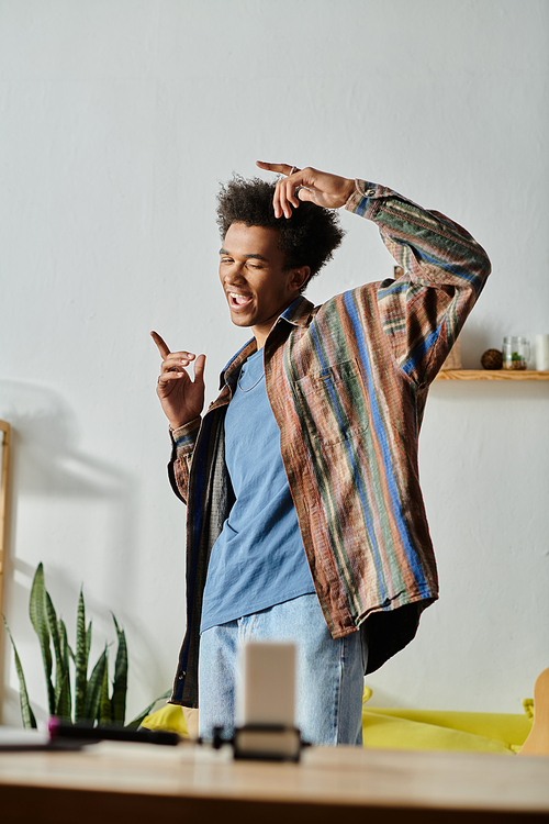 Young African American male blogger standing in living room with hands in pockets, talking on phone camera.