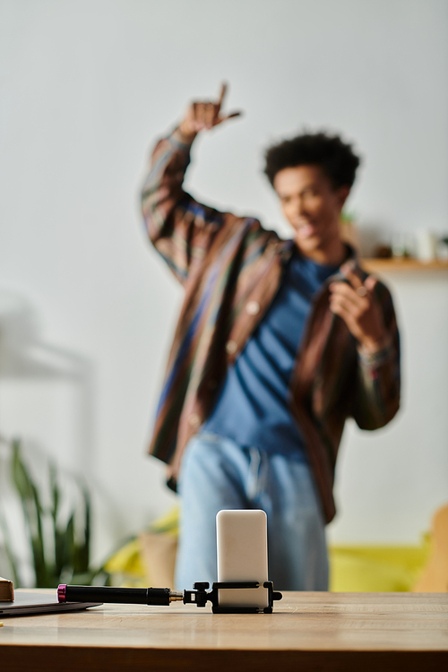 Young African American man stands on table, phone in hand, blogger vlogging.