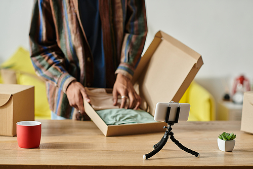 A man revealing the contents of a box while sitting at a table.