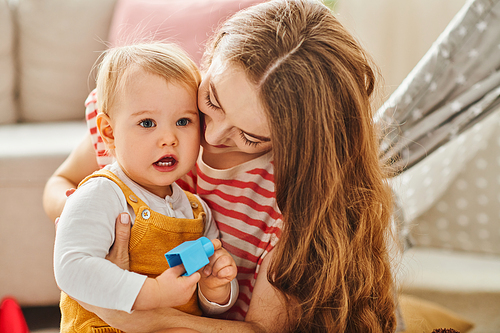 A young mother tenderly holds her toddler daughter in her arms, expressing love and bonding.