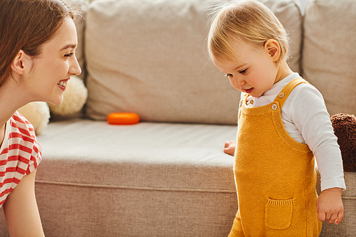 A young mother smiles at her toddler daughter as they enjoy precious time together.