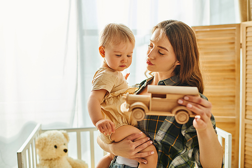 A young mother tenderly holding her toddler daughter in her arms, showcasing the unbreakable bond between them.