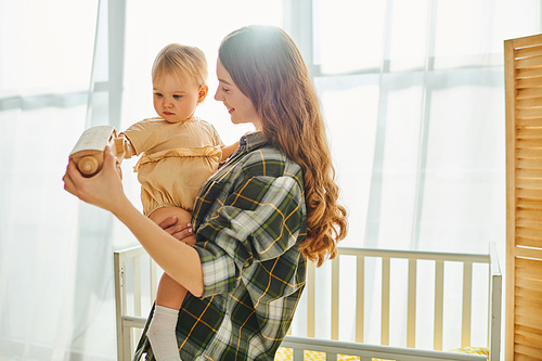 A young mother lovingly holds her toddler daughter in her arms, creating a heartwarming moment of connection and affection.