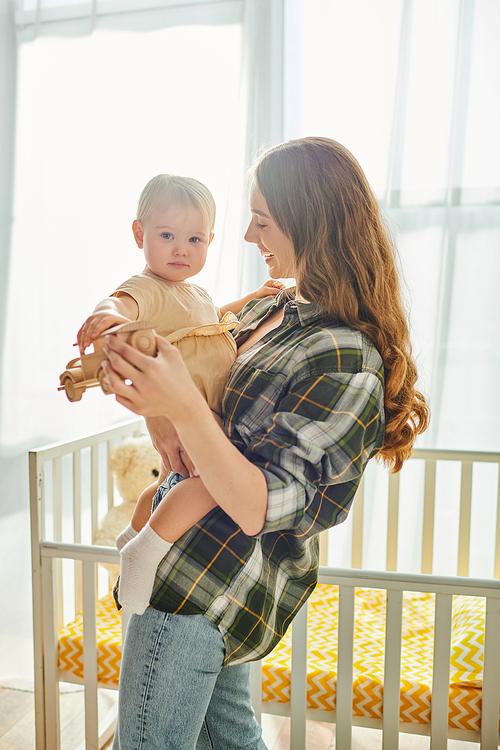 A young mother tenderly cradles her toddler daughter in her arms, showcasing an unbreakable bond filled with love and care.