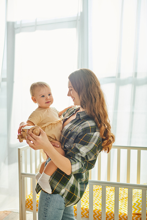 A young mother lovingly cradles her toddler daughter in her arms, sharing a sweet moment of connection and love at home.