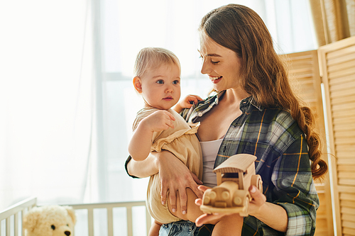 A young mother cradling her toddler daughter in her arms, showing love and affection in a warm home setting.