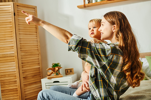 A mother and her toddler daughter pointing with excitement at something off-screen.