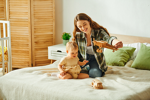 A young mother cherishes quality time with her toddler daughter as they play together on a bed.