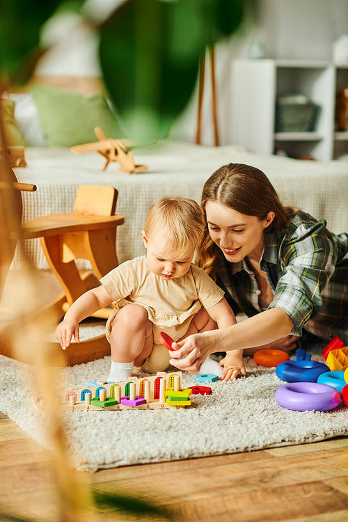 A young mother joyfully engages with her toddler daughter on the floor, fostering a strong bond through play and interaction.