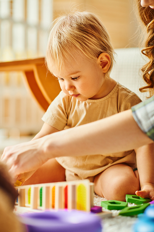 A young mother joyfully playing with her toddler daughter on the floor at home.