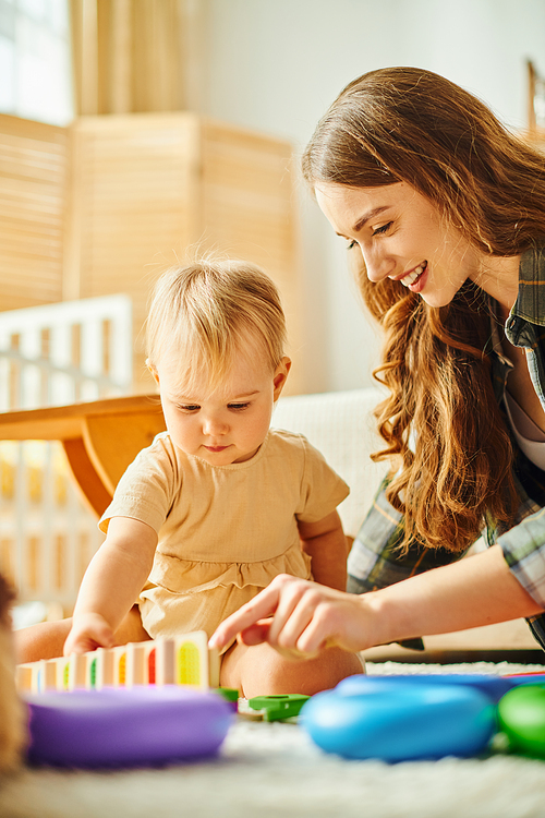 A young mother lovingly interacts with her toddler daughter on the floor, creating joyful moments of bonding and play.