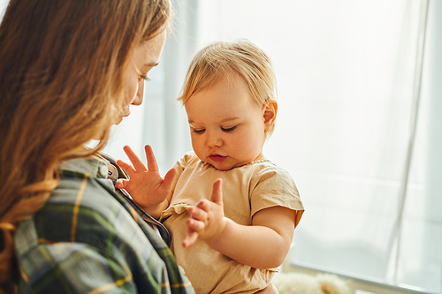 A young mother tenderly holding her toddler daughter in her lap, radiating love and warmth in their intimate moment together.