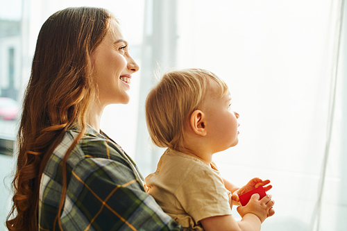 A young mother cherishes the special bond with her toddler daughter, holding her lovingly in her arms at home.