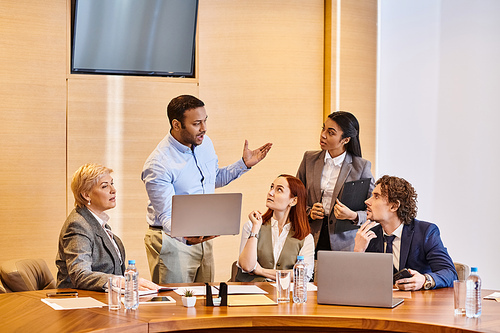 Multicultural business professionals brainstorm around a conference table.