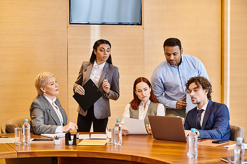 Business professionals of different backgrounds collaborate at conference table.