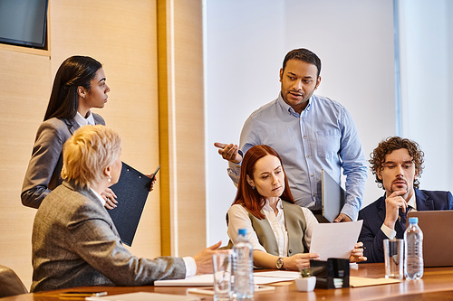 Diverse group of business professionals brainstorming around conference table.