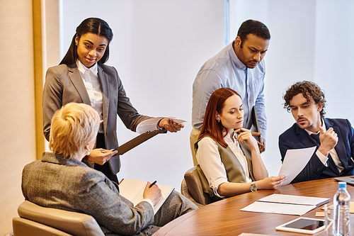 Diverse group of business professionals engaged in a meeting around a conference table.