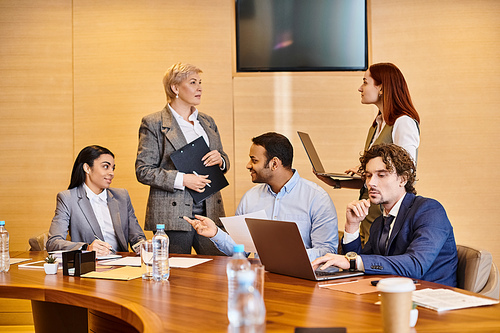 An interracial group of business professionals discussing strategy at a conference table.