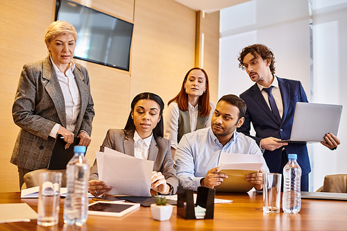 Diverse businesspeople of different races standing around a conference table, discussing ideas.