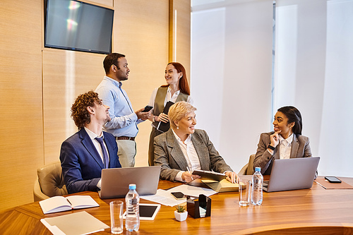 Diverse group of people discussing in a professional meeting around a conference table.