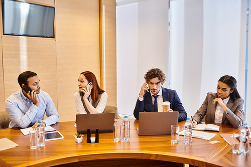 Diverse group of business professionals collaborating with laptops at table.