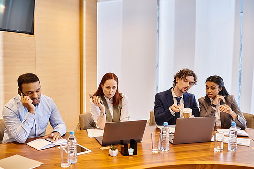 Diverse business professionals working on laptops at a table.