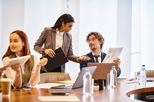 An interracial group of business professionals engaged in a meeting around a conference table.