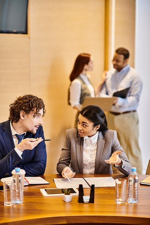 A diverse group of business people brainstorming around a wooden table.