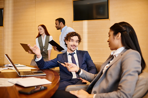 Diverse group of business professionals engaged in a discussion at a conference table.