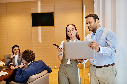 Diverse business professionals collaborate around a table with a laptop.