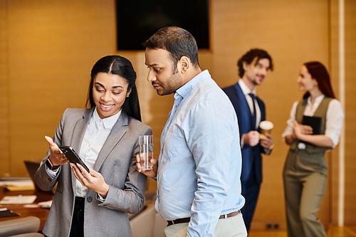 An interracial man and woman engage with a cell phone.