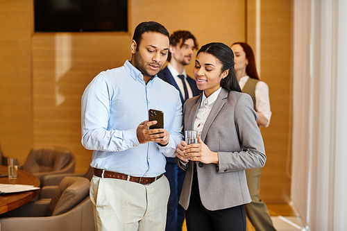 A man and woman of different ethnicities engrossed in a cell phone together.