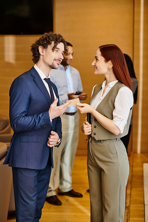 A stylish man and woman in business suits stand side by side.