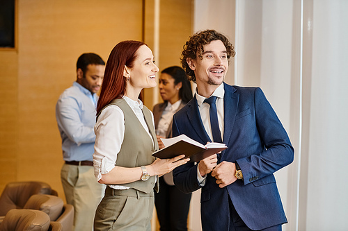 A man and woman stand as a man holds a book before them.