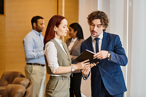 A man and a woman stand in front of a man in a suit in a business setting.