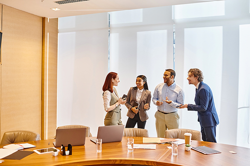 Multicultural business team discuss ideas around conference table.